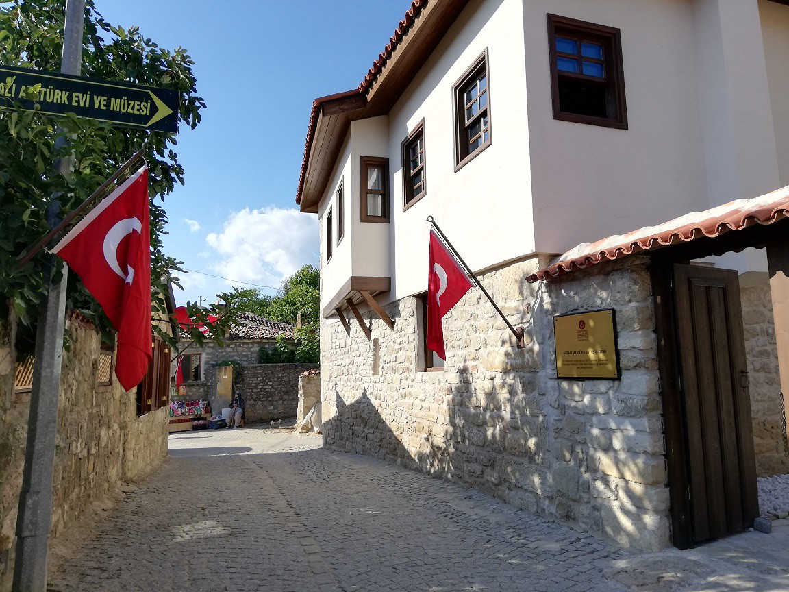 KÖYÜN KALBİ, MEDYANINDA ATIYORDirekt köyün meydanına giriş yapıyoruz. Karşımıza kocaman bir alan çıkıyor. Toprak zemin yok. Yerler granit taşlarla bezeli. Evlerin yönü meydana bakıyor. Evler tek, en fazla da iki katlı yapılmış. Çevredeki taş binalar çok bakımlı. Pencerelerin ahşapları yeni, çatıları düzgün. Etrafta banklar gibi bazı şehir mobilyaları göze çarpıyor.