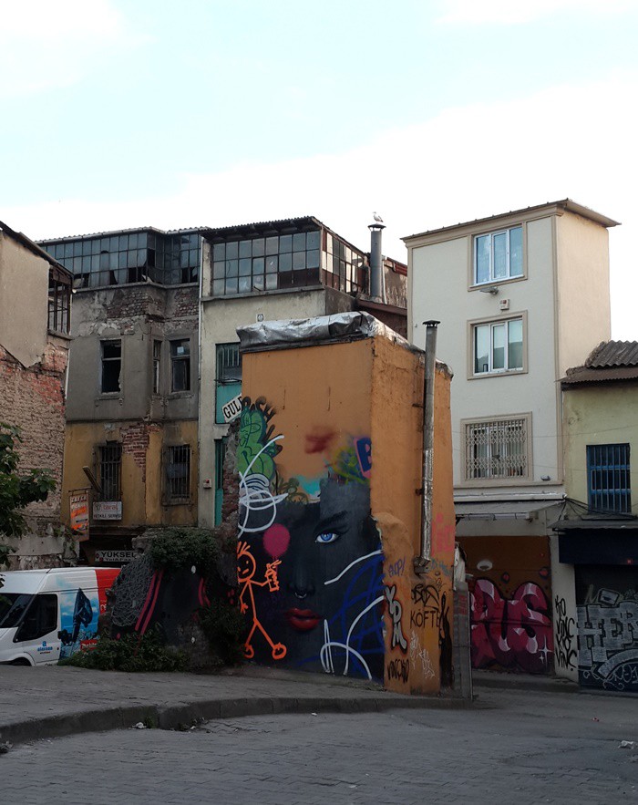 Grafiti sanatçılarının binaları kepenkleri bir sanat galerisi titizliği ile işlediği adanın doğası farklıdır. Bir gün tamamen yok olacak harabe binaların arasındaki çırpınış bitecektir. Bu bilinmektedir. Ama hiçbir şey olmayacakmış gibi didinmeye devam edilmektedir. Başka ezberi olmayan insanların, nefes aldığı adayı son gününe kadar yaşamak arzusu saklıdır dükkanların kepeklerinde. Balık ekmekçileri, salaş ama bir o kadar çekici lokantası olan bölge yine de çok sessizdir. Suratlar da asık. Belki de bu yıkıma, yer değiştirmeye bir direnme biçimidir. Son ana kadar dükkanlarında olan insanların inatçı sevgisi beni kendisine hayran bırakır.